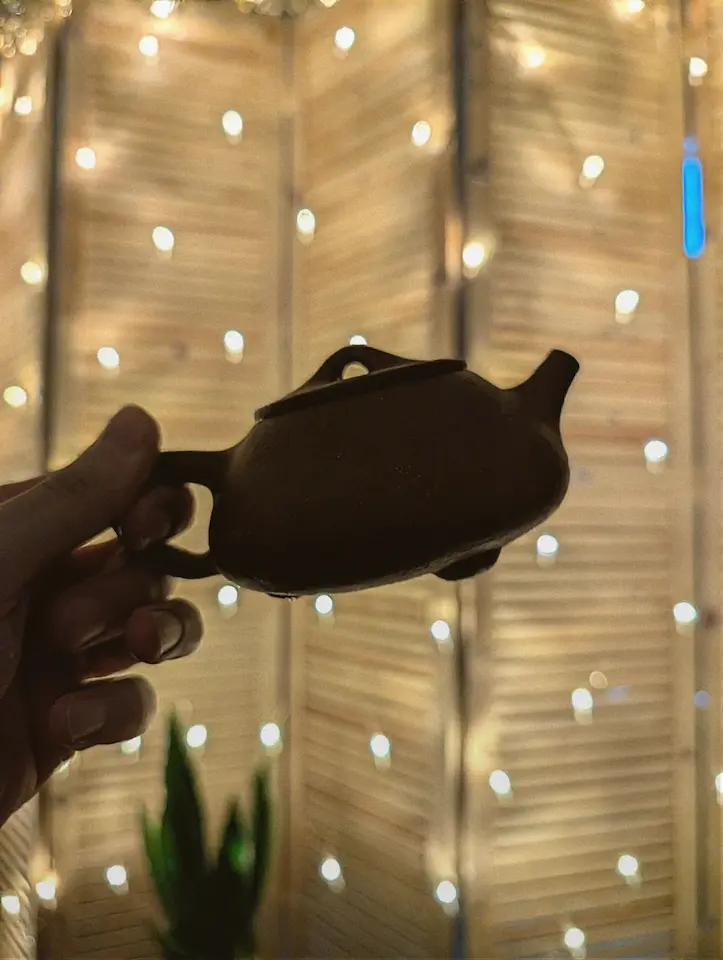 Чайник в темноте на светлом фоне гирлянд